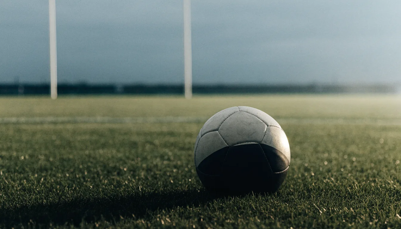 Ein Fussball auf dem Rasen aus niedriger Perspektive aufgenommen, die Torpfosten verschwimmen im Hintergrund.