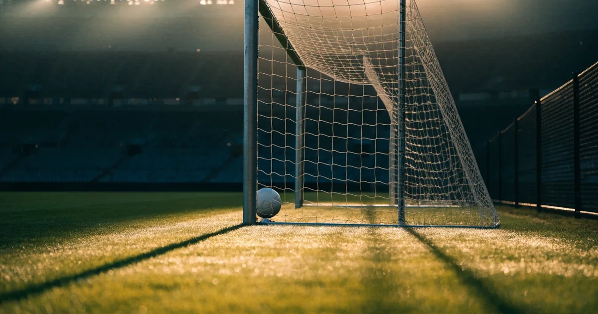 Ein Fussballtor mit weissem Netz steht auf frisch gemähtem Rasen, die hellen und dunklen Streifen im Gras leuchten im Gegenlicht.